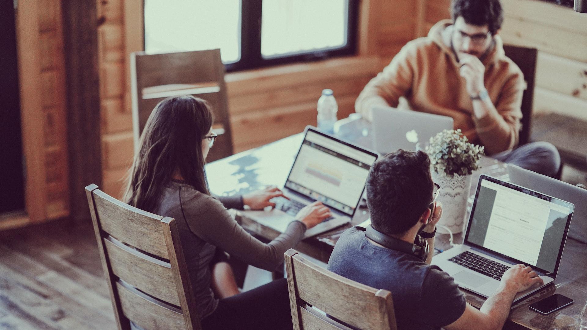 selective focus photography of woman and man using MacBook Pro on table